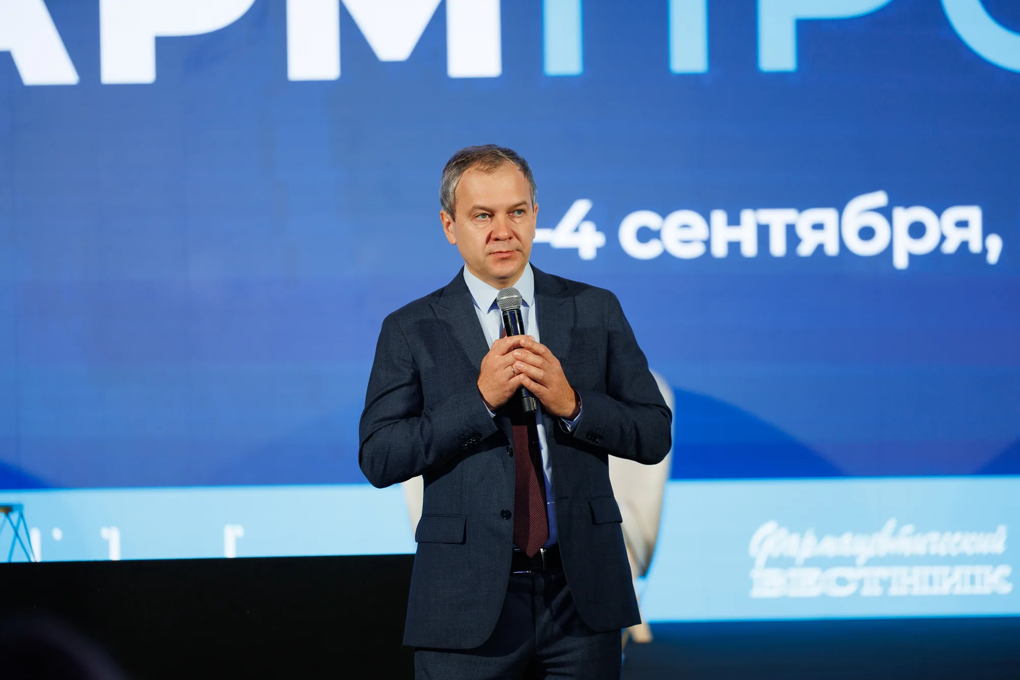 Выступление спикера на фоне оформления конференции